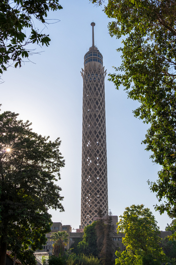 View of the towering Cairo Tower a latticed structure piercing the sky framed by lush green trees under a bright sun Zamalek Cairo Governorate Egypt. View of the towering Cairo Tower a latticed structure piercing the sky framed by lush green trees under a bright sun Zamalek Cairo Governorate Egypt.