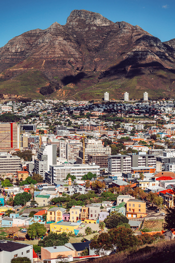 View of the colorful Bo Kaap neighborhood and city skyline with Table Mountain in the background under a clear blue sky in Cape Town Western Cape South Africa. View of the colorful Bo Kaap neighborhood and city skyline with Table Mountain in the background under a clear blue sky in Cape Town Western Cape South Africa.