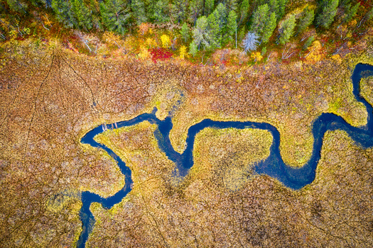 Aerial view of a winding river flowing through a marshy landscape with vibrant autumn foliage and dense forest in Enontekio Lapland Finland. Aerial view of a winding river flowing through a marshy landscape with vibrant autumn foliage and dense forest in Enontekio Lapland Finland.