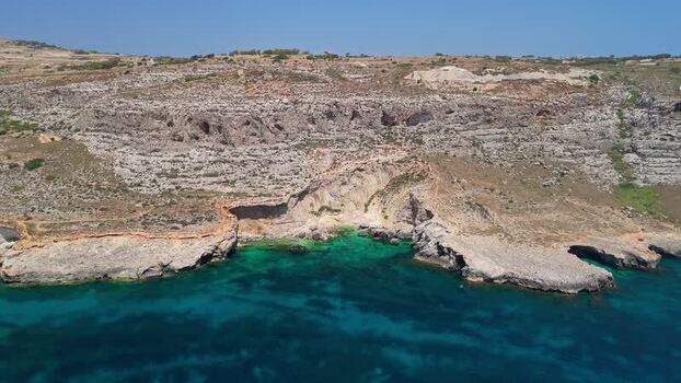 Aerial view of Ghar Lapsi Malta with cliffs rocky bay and cave entrance Aerial view of Ghar Lapsi Malta with cliffs rocky bay and cave entrance