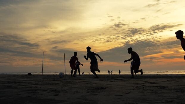 View of people playing football on the beach at sunset Bangladesh. View of people playing football on the beach at sunset Bangladesh.
