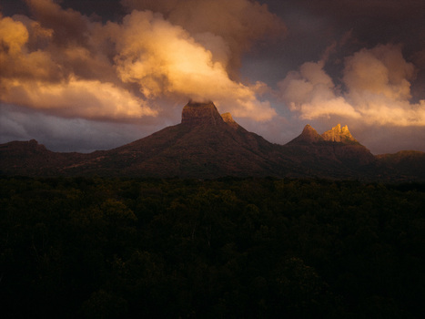 Aerial view of the Moka Range mountains with dramatic peaks partially covered by clouds during golden hour over a dense forest in Moka District Mauritius. Aerial view of the Moka Range mountains with dramatic peaks partially covered by clouds during golden hour over a dense forest in Moka District Mauritius.