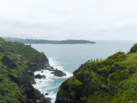 Aerial view of the dramatic cliff edge where land meets the sea with a distant island on the horizon at Pengilon Hill Gunungkidul Regency Daerah Istimewa Yogyakarta Indonesia. Aerial view of the dramatic cliff edge where land meets the sea with a distant island on the horizon at Pengilon Hill Gunungkidul Regency Daerah Istimewa Yogyakarta Indonesia.