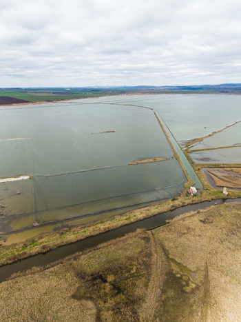 Aerial view of Lake Atanasovsko featuring salt pans narrow water channels and a small building under a cloudy sky in Burgas Burgas Bulgaria. Aerial view of Lake Atanasovsko featuring salt pans narrow water channels and a small building under a cloudy sky in Burgas Burgas Bulgaria.