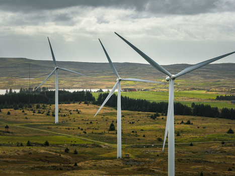 Aerial view of Hog Jaeren wind farm with large white wind turbines standing in rolling green hills under a cloudy sky in Ha Municipality Rogaland Norway. Aerial view of Hog Jaeren wind farm with large white wind turbines standing in rolling green hills under a cloudy sky in Ha Municipality Rogaland Norway.