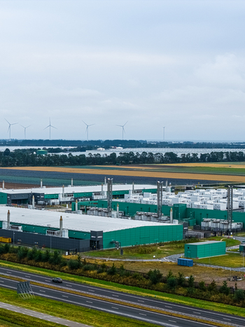 Aerial view of Agriport A7 data center complex with green buildings surrounding fields wind turbines and a highway in the foreground in Middenmeer Noord Holland Netherlands. Aerial view of Agriport A7 data center complex with green buildings surrounding fields wind turbines and a highway in the foreground in Middenmeer Noord Holland Netherlands.