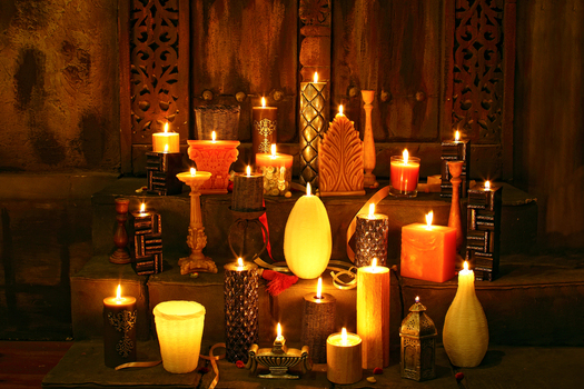 View of an assortment of decorative candles of various shapes sizes and textures glowing warmly on stone steps in a dimly lit room in Lahore Punjab Pakistan.
