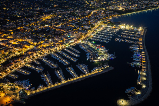 Aerial view of the illuminated Port Vauban marina at night featuring numerous yachts docked in the harbor surrounded by glowing city lights in Antibes Provence Alpes Cote d Azur France. Aerial view of the illuminated Port Vauban marina at night featuring numerous yachts docked in the harbor surrounded by glowing city lights in Antibes Provence Alpes Cote d Azur France.