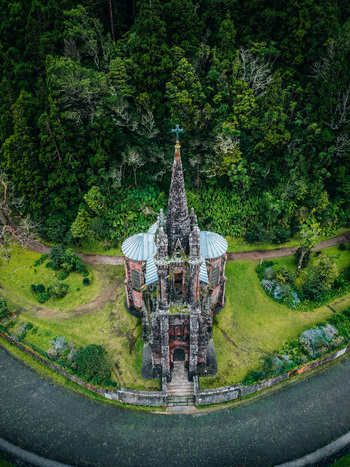 Aerial view of an old church with a cross on top surrounded by green trees and grass Furnas Azores Portugal.