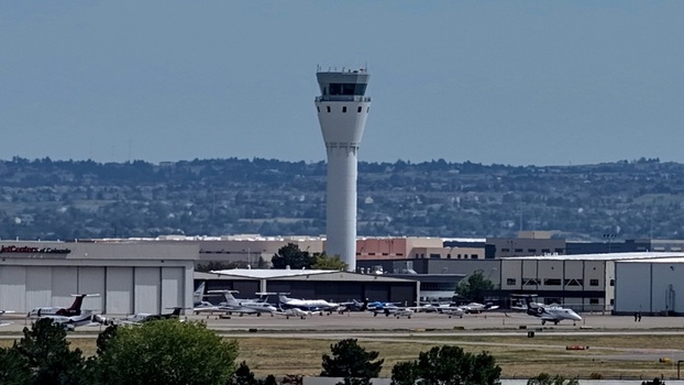 Aerial view of the air traffic control tower at Centennial Airport with various private jets parked on the tarmac in Centennial Colorado United States.