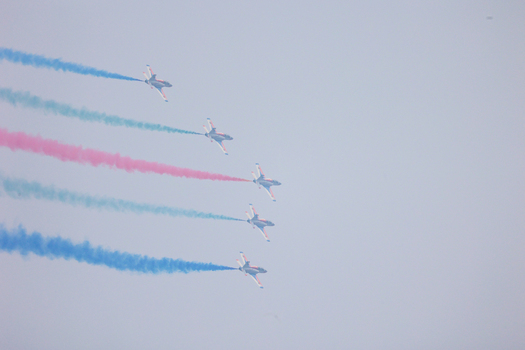 Dhaka Bangladesh 25 March 2026 View of vibrant plumes of red blue and green smoke trailing behind fighter jets against a pale sky a spectacle of aerial artistry.