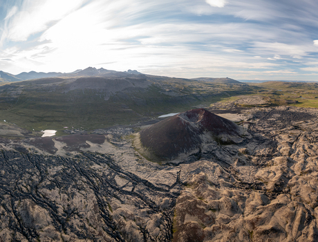Aerial view of Ytri Raudarmelskula volcanic crater surrounded by vast lava fields rugged terrain and distant mountains in Raudhamelur Eyja og Miklaholtshr Iceland. Aerial view of Ytri Raudarmelskula volcanic crater surrounded by vast lava fields rugged terrain and distant mountains in Raudhamelur Eyja og Miklaholtshr Iceland.
