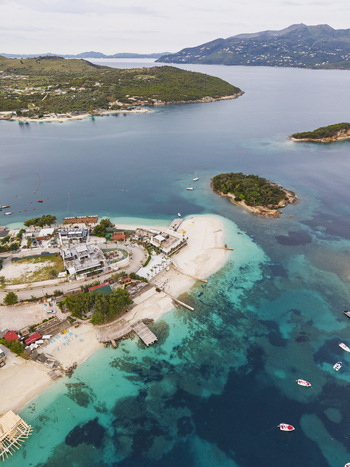 Aerial view of the turquoise waters sandy beaches and small islands of Ksamil featuring coastal buildings and boats in the Ionian Sea Ksamil Vlore County Albania. Aerial view of the turquoise waters sandy beaches and small islands of Ksamil featuring coastal buildings and boats in the Ionian Sea Ksamil Vlore County Albania.