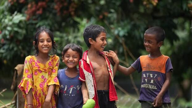View of smiling children in a lush orchard Bangladesh.