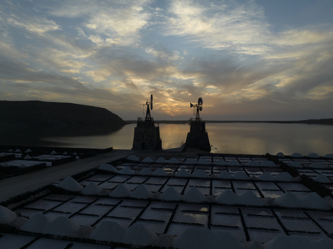 Aerial view of Salinas de Janubio salt pans at sunset with traditional windmills and geometric salt piles in Yaiza Lanzarote Spain. Aerial view of Salinas de Janubio salt pans at sunset with traditional windmills and geometric salt piles in Yaiza Lanzarote Spain.