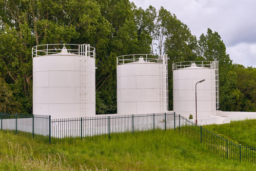 Wieringerwerf Netherlands 17 May 2026 View of Gemaal Leemans featuring three white industrial storage tanks with safety ladders surrounded by a green fence and lush trees.