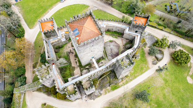Aerial view of Guimaraes Castle with its medieval stone towers and orange tiled roofs surrounded by lush green lawns in Guimaraes Braga Portugal. Aerial view of Guimaraes Castle with its medieval stone towers and orange tiled roofs surrounded by lush green lawns in Guimaraes Braga Portugal.