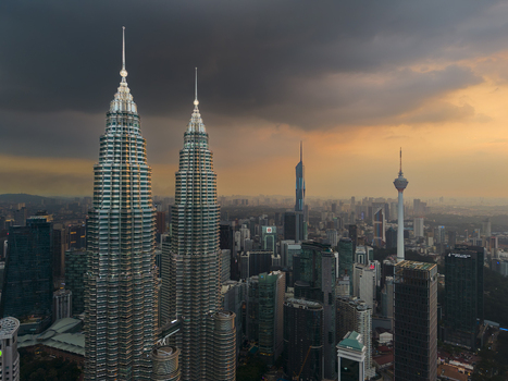Kuala Lumpur Malaysia 11 March 2026 Aerial view of the Petronas Twin Towers and the city skyline under a dramatic sunset sky with dark storm clouds.