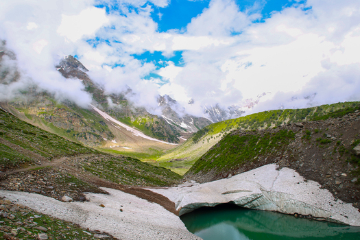 View of Rama Meadows featuring a glacial lake snow capped mountains and lush green slopes under a cloudy sky in Astore Gilgit Pakistan. View of Rama Meadows featuring a glacial lake snow capped mountains and lush green slopes under a cloudy sky in Astore Gilgit Pakistan.