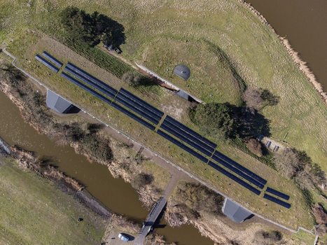 Aerial view of dark solar panels contrast against the green grassy field next to the canal Naarden North Holland Netherlands. Aerial view of dark solar panels contrast against the green grassy field next to the canal Naarden North Holland Netherlands.