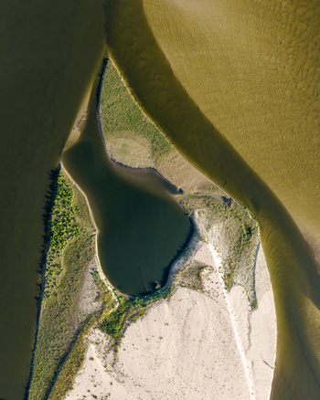 Aerial view of Zawadowskie Islands Nature Reserve featuring sandy riverbanks lush green vegetation and calm water patterns in Masovian Voivodeship Poland.