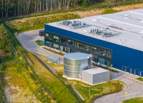 Aerial view of a modern industrial building with a large metal water tank paved parking area and surrounding green space in Kowale Pomeranian Voivodeship Poland. Aerial view of a modern industrial building with a large metal water tank paved parking area and surrounding green space in Kowale Pomeranian Voivodeship Poland.