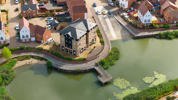Aerial view of a modern residential housing estate featuring brick houses and apartment buildings situated along a riverbank with a wooden pier in Bedford England United Kingdom. Aerial view of a modern residential housing estate featuring brick houses and apartment buildings situated along a riverbank with a wooden pier in Bedford England United Kingdom.