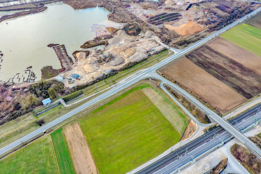 Aerial view of a gravel pit and quarry next to a lake with railway tracks and agricultural fields in Forchheim Bavaria Germany. Aerial view of a gravel pit and quarry next to a lake with railway tracks and agricultural fields in Forchheim Bavaria Germany.