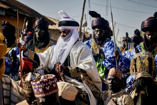 Zaria City Nigerian 21 March 2026 View of a majestic traditional leader in brilliant white and gold regalia on horseback leading a vibrant procession amidst a crowd under a clear sky. Zaria City Nigerian 21 March 2026 View of a majestic traditional leader in brilliant white and gold regalia on horseback leading a vibrant procession amidst a crowd under a clear sky.