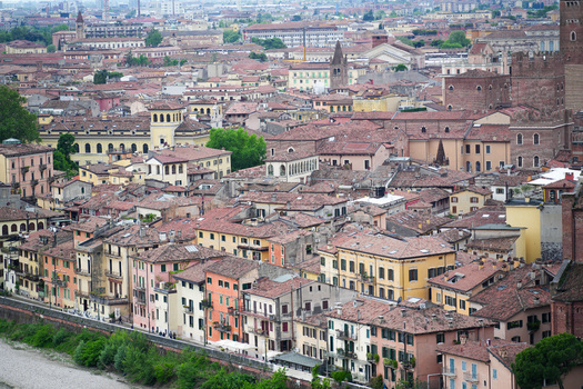 Aerial view of the historic old town featuring dense terracotta rooftops and colorful buildings along the riverbank Verona Veneto Italy.