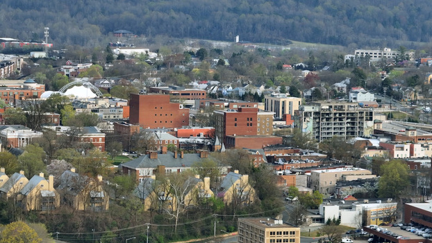 Aerial view of the cityscape of Charlottesville featuring a mix of historic brick buildings residential homes and lush spring foliage in Charlottesville Virginia United States.