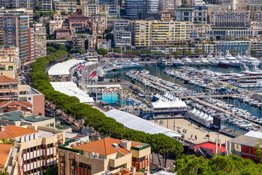 View of Port Hercules in Monaco City with luxury yachts white event tents and surrounding urban architecture Monaco City Monaco. View of Port Hercules in Monaco City with luxury yachts white event tents and surrounding urban architecture Monaco City Monaco.