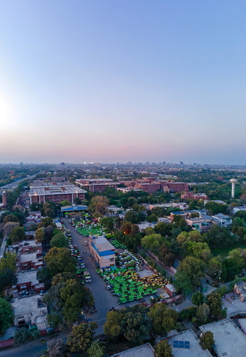 Aerial view of an urban landscape featuring a large lot filled with green rickshaws and surrounding buildings under a clear sky at dusk in Lahore Punjab Pakistan. Aerial view of an urban landscape featuring a large lot filled with green rickshaws and surrounding buildings under a clear sky at dusk in Lahore Punjab Pakistan.