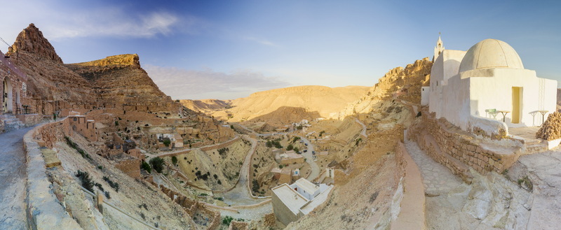 View of the historic hilltop village of Chenini with traditional white domed architecture and stone dwellings carved into the rocky desert landscape in Tataouine Tataouine Governorate Tunisia.