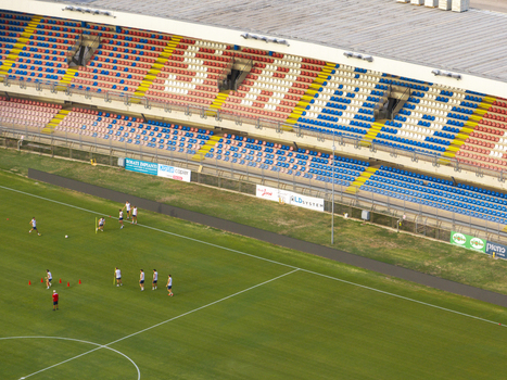 Aerial view of Stadio Riviera delle Palme with soccer players training on the green pitch and colorful stadium seating in San Benedetto del Tronto Marche Italy.