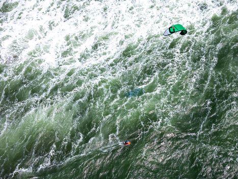 Aerial view of a kitesurfer gliding over the churning green waves of Depok Beach in the Special Region of Yogyakarta Indonesia.