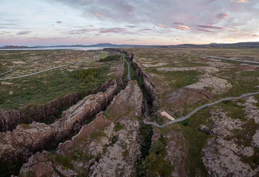 Aerial view of the dramatic tectonic rift and volcanic landscape of Thingvellir National Park with mossy rocks and a walking path under a soft sky in Selfoss Blaskogabyggd Iceland. Aerial view of the dramatic tectonic rift and volcanic landscape of Thingvellir National Park with mossy rocks and a walking path under a soft sky in Selfoss Blaskogabyggd Iceland.