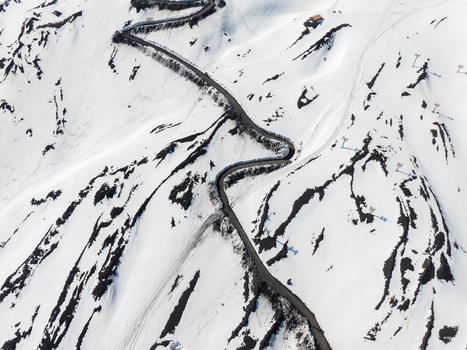 Aerial view of the winding road on the snow covered south slope of Mount Etna with volcanic rock and ski lift poles in Nicolosi Sicilia Italy. Aerial view of the winding road on the snow covered south slope of Mount Etna with volcanic rock and ski lift poles in Nicolosi Sicilia Italy.