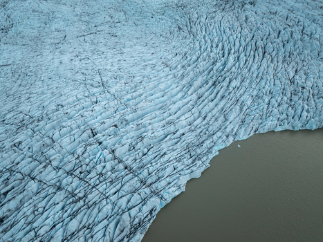 Aerial view of the crevassed ice surface of Heinabergsjokull glacier meeting the glacial lake in Sveitarfelagid Hornaf Iceland.