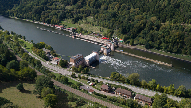 Aerial view of Neckar Staustufe und Schleuse Rockenau dam and lock system on the Neckar river surrounded by dense forests and green hills in Eberbach Baden Wurttemberg Germany. Aerial view of Neckar Staustufe und Schleuse Rockenau dam and lock system on the Neckar river surrounded by dense forests and green hills in Eberbach Baden Wurttemberg Germany.