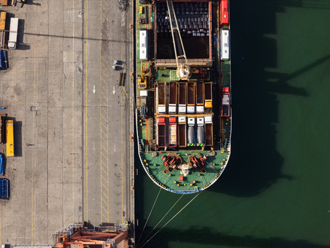 Aerial view of a cargo ship docked at the industrial port with containers and trucks on the pier in Bajos de Haina San Cristobal Provinc Dominican Republic.