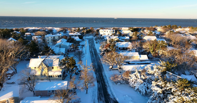 Aerial view of snow covered houses and trees along a coastal road leading to the ocean in Cape May New Jersey United States.