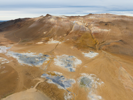 Aerial view of geothermal area with vibrant orange and yellow hillsides contrasting with the pale blue of the mineral pools Reykjahl&iacute;&eth; &THORN;ingeyjarsveit Iceland.