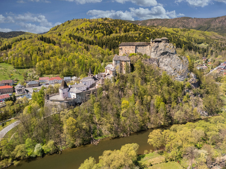 Aerial view of Orava Castle perched on a high rock cliff above the Orava river surrounded by lush green forests and a small village in Dolny Kubin Zilinsky kraj Slovakia. Aerial view of Orava Castle perched on a high rock cliff above the Orava river surrounded by lush green forests and a small village in Dolny Kubin Zilinsky kraj Slovakia.
