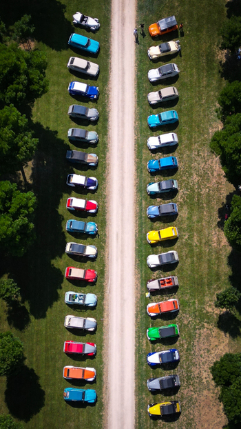 Francheleins France 04 June 2023 Aerial view of Chateau de Vataneins grounds with colorful vintage cars parked along a central path on green grass with people walking nearby. Francheleins France 04 June 2023 Aerial view of Chateau de Vataneins grounds with colorful vintage cars parked along a central path on green grass with people walking nearby.
