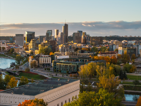 Aerial view of the modern skyline piercing through the golden hues of autumn foliage with the Neris River winding its way through the city s heart Vilnius Lithuania. Aerial view of the modern skyline piercing through the golden hues of autumn foliage with the Neris River winding its way through the city s heart Vilnius Lithuania.