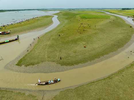 Aerial view of meandering waterways carve through the vibrant green landscape with boats gliding along the river Charmonai Barisal Division Bangladesh. Aerial view of meandering waterways carve through the vibrant green landscape with boats gliding along the river Charmonai Barisal Division Bangladesh.
