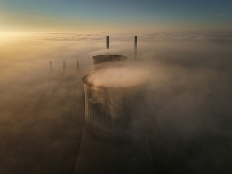 Aerial view of the RWE Clauscentrale power plant cooling towers and chimneys emerging from a thick layer of morning fog at sunrise in Maasbracht Limburg Netherlands. Aerial view of the RWE Clauscentrale power plant cooling towers and chimneys emerging from a thick layer of morning fog at sunrise in Maasbracht Limburg Netherlands.