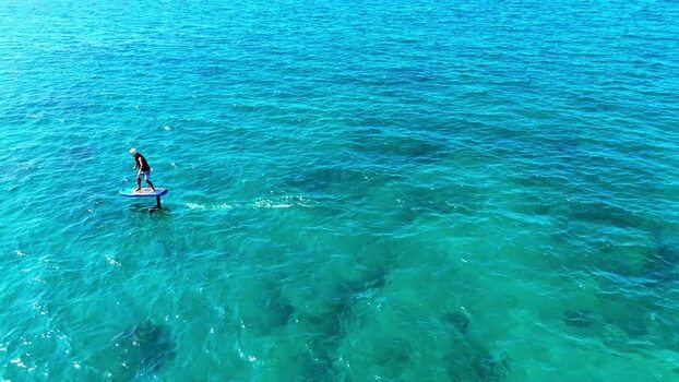 Aerial view of a man riding an e foil on blue water United States. Aerial view of a man riding an e foil on blue water United States.