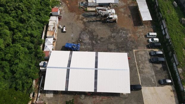 Aerial view of the Bambu Apus site featuring a large white warehouse roof construction machinery and parked vehicles in Kecamatan Cipayung Daerah Khusus Ibukota Indonesia. Aerial view of the Bambu Apus site featuring a large white warehouse roof construction machinery and parked vehicles in Kecamatan Cipayung Daerah Khusus Ibukota Indonesia.
